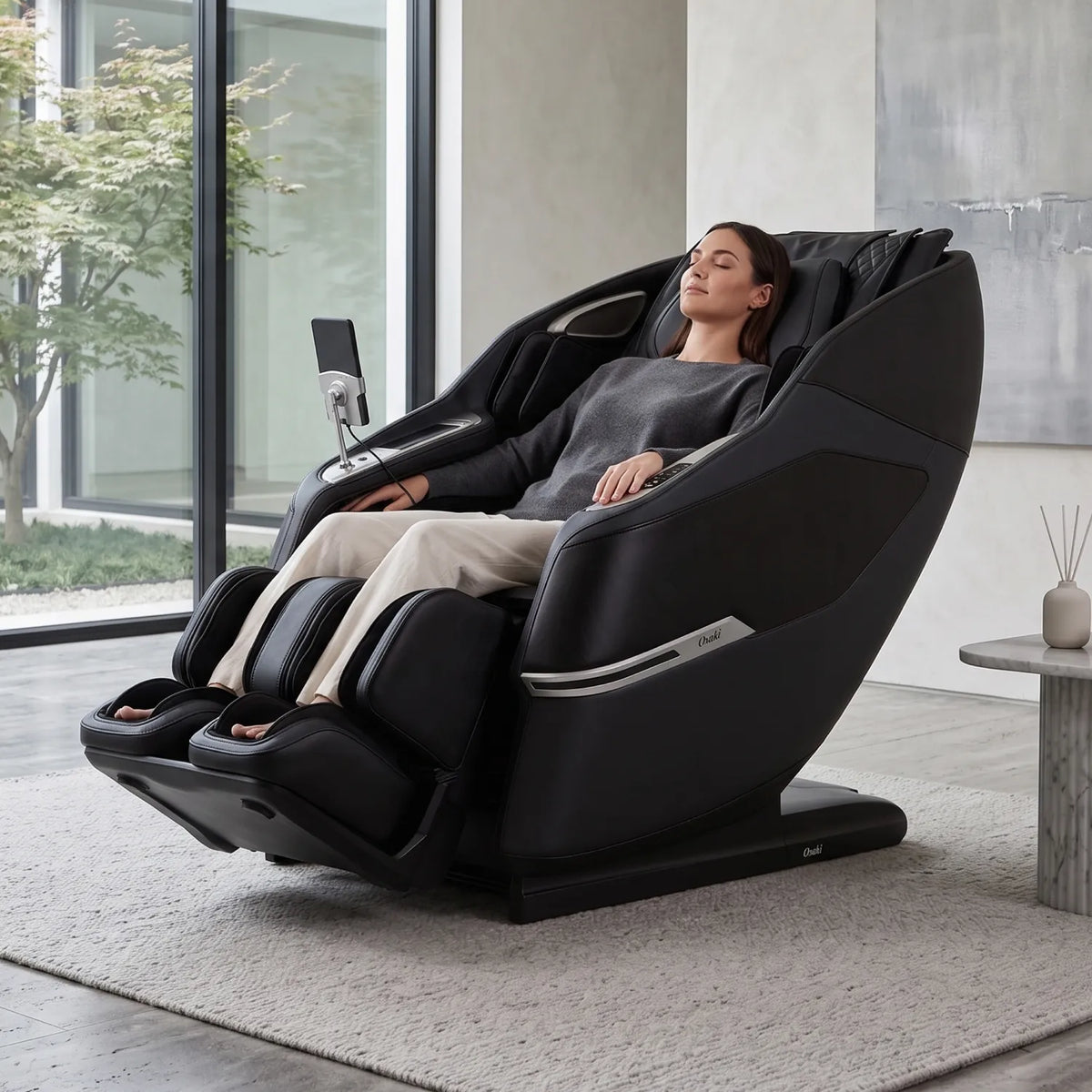 Woman reclining in a Black Osaki Aeris 4D Duo massage chair in a bright living room with large windows